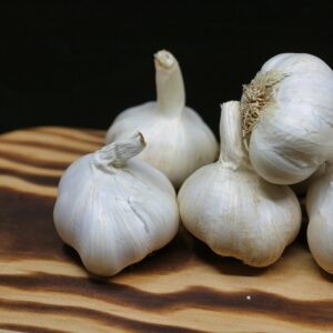 Fresh garlic bulbs placed on a wooden board with a black background, perfect for culinary themes.