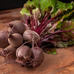 Home Bundle of fresh organic beetroots with vibrant green leaves on a wooden surface.
