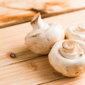 Fresh white mushrooms on a wooden table, showcasing natural textures and earthy tones.