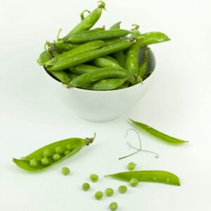 A white ceramic bowl filled with fresh green peas and pea pods on a light background.